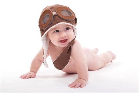 Desnudo lindo bebé sonriente en la tapa del piloto está volando en un w