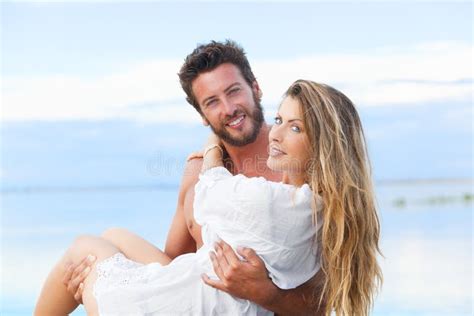 Man Holding Woman In His Arms Under A Blue Sky On Seaside Stock Photo