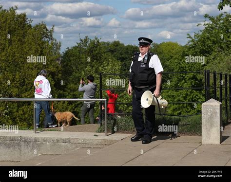 A Police Officer With A Megaphone Instructs People To Keep Moving In