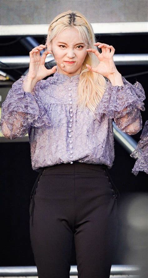 A Woman With Blonde Hair Wearing Black Pants And A Purple Top Is