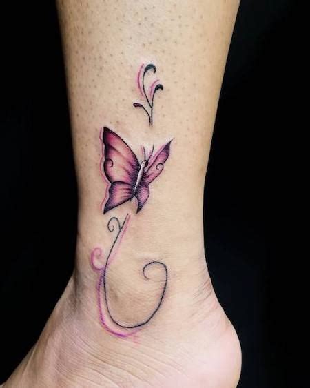 a small butterfly tattoo on the ankle with pink flowers and swirls in ...