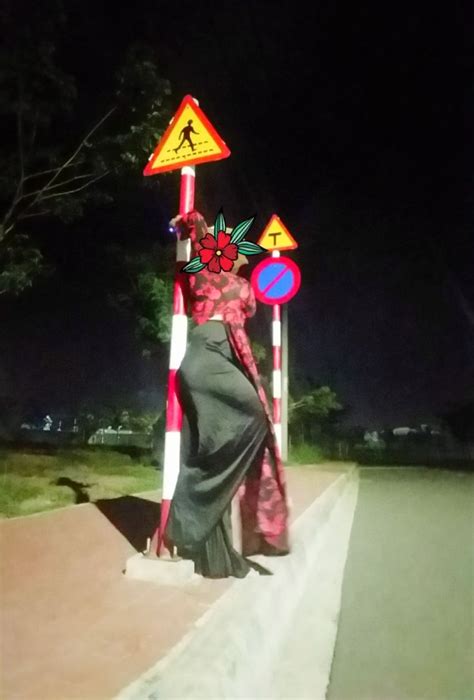 A Woman In A Long Dress Is Standing On The Side Of A Road At Night