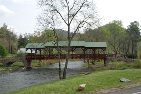 A Red Bridge Over A River Next To A Lush Green Forest