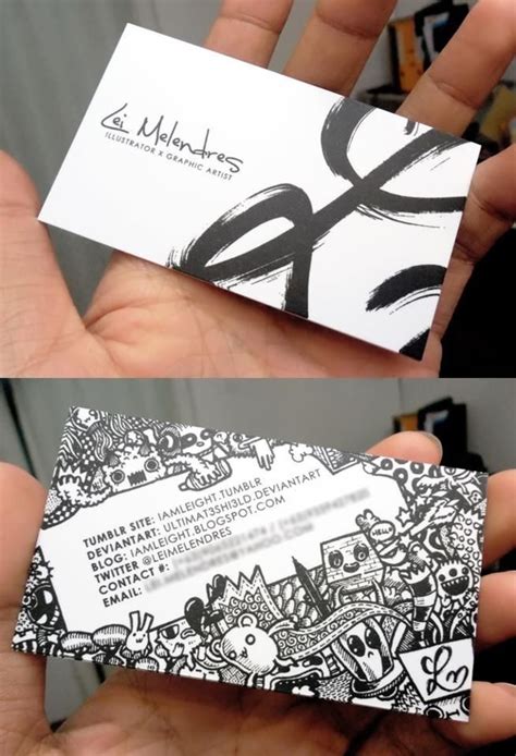 Two Business Cards With Black And White Designs In The Palm Of Someone