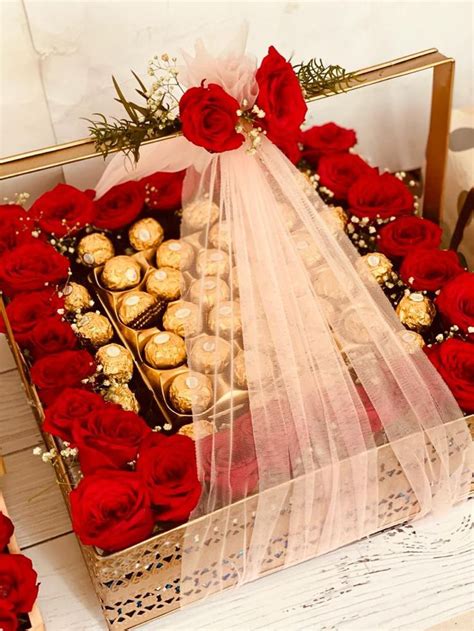 A Box Filled With Chocolates And Red Roses