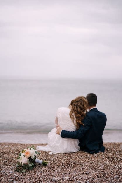 Premium Photo Groom Hugs Bride In A White Dress Sitting With Her On A