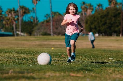 Premium Photo | Boy child kicking football on the sports field during ...