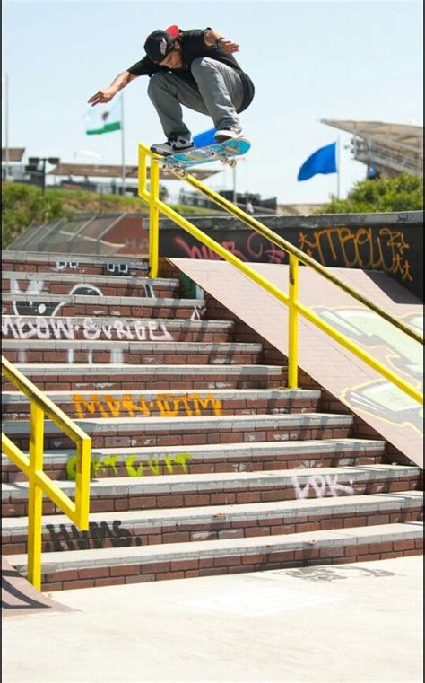 A Man Riding A Skateboard Down The Side Of A Metal Rail Next To Stairs