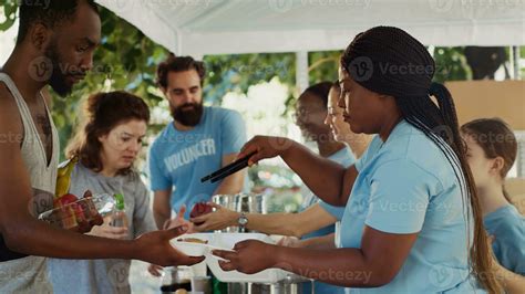 Side-view of young volunteers serving meals to those in need, helping