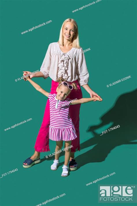 Portrait Mother And Daughter Holding Hands Against Green Background