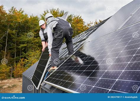 Workers Lifting Up Photovoltaic Solar Module While Installing Solar