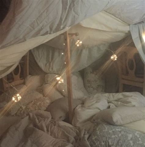 An Unmade Bed With White Sheets And Lights On The Headboard In A Bedroom