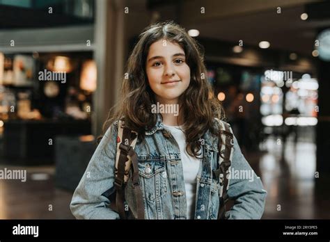 Portrait of smiling girl with long hair wearing denim jacket at station ...