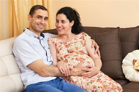 Pregnant Woman And Man Indoor Portrait Happy People Sit On Sofa Stock