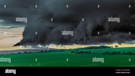 Green field with thunderous black clouds hanging low over it just before a tornado Stock Photo ...