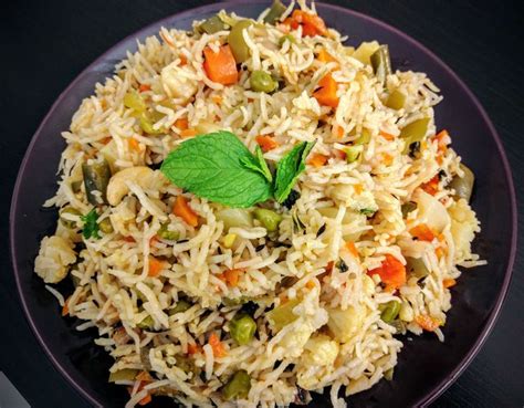 a plate full of rice and vegetables with a green leaf on the top is ...