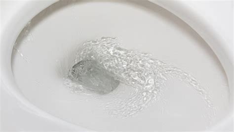 A White Toilet Bowl With Water Coming Out Of The Lid And Seat Cover In