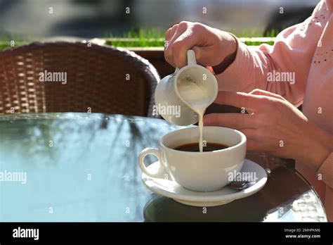 Woman Pouring Milk In Coffee At Table In Cafe Stock Photo Alamy