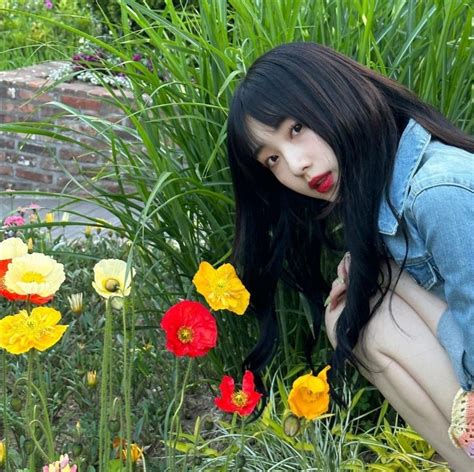 A Woman Kneeling Down In Front Of Flowers