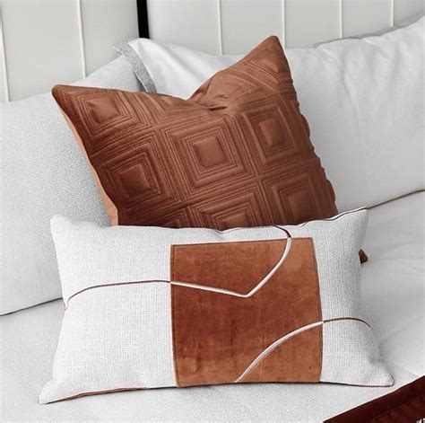 Two Brown And White Pillows Sitting On Top Of A Bed Next To Eachother