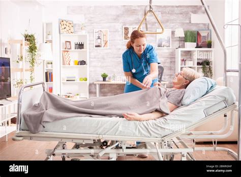 Female Doctor In Ursing Home Taking Care Of Old Woman Lying In Bed