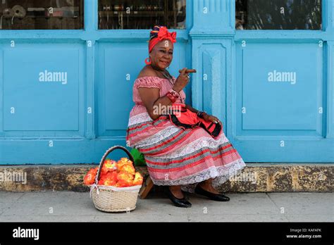 A Colourfully Dressed Cuban Woman In Traditional Clothing Sits On The