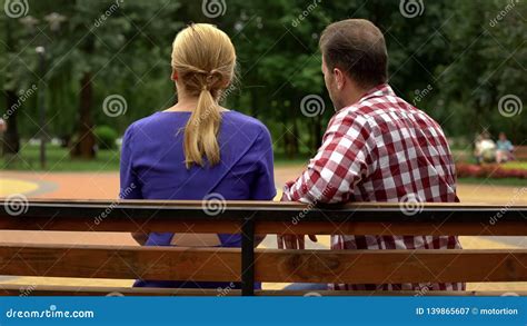 Back View Of Couple Sitting On Park Bench Spending Time Together Conversation Stock Image