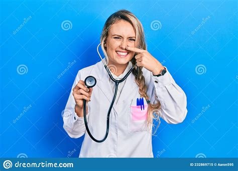 Beautiful Young Blonde Doctor Woman Holding Stethoscope Pointing With