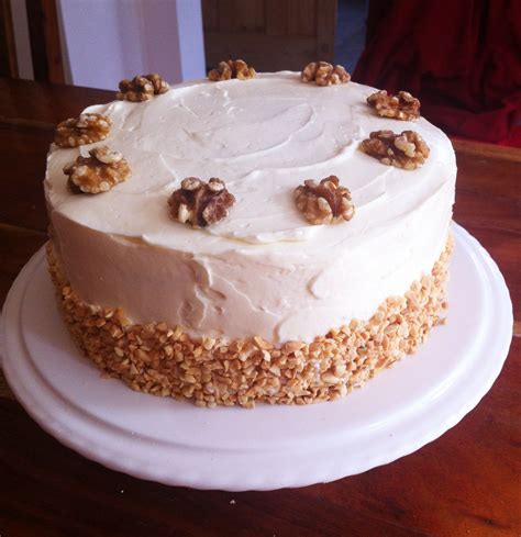 A Cake With White Frosting And Walnuts On Top