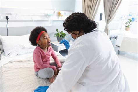 African American Female Doctor Wearing Face Mask Examining Girl Patient