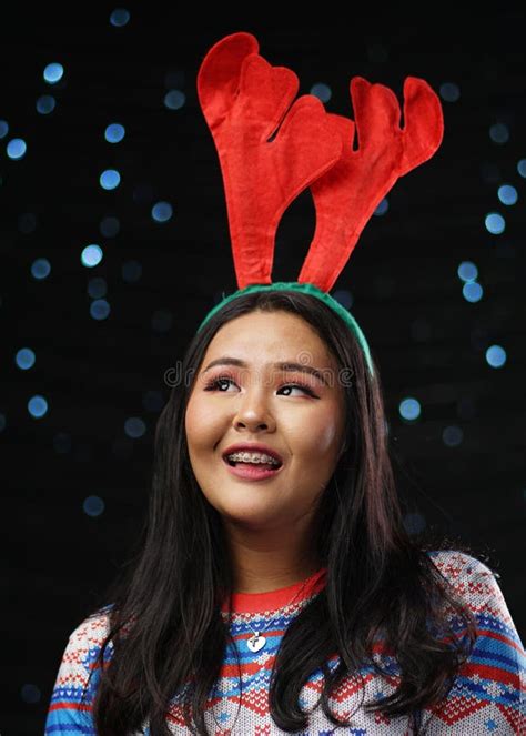 Asian Girl Wearing Christmas Sweater And Reindeer Horns Headband Stock