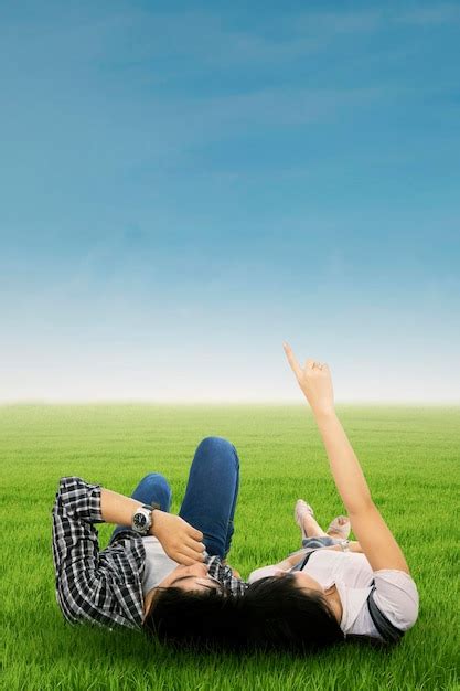 Premium Photo Couple Lying On Grass Pointing At Sky