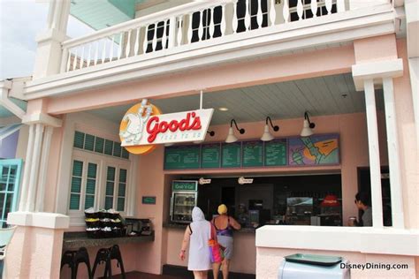 two people are standing in front of a food stand that is pink and white with the words good's on it