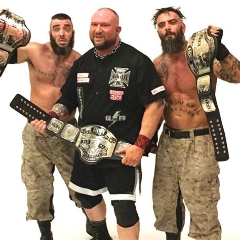 Three Men Standing Next To Each Other Holding Wrestling Belts