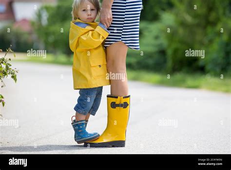 Mother And Toddler Child Boy Playing In The Rain Wearing Boots And