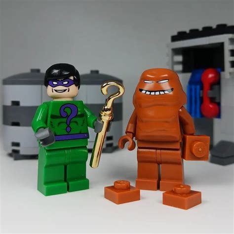 Two Lego Figurines Standing Next To Each Other With One Holding A Gold Key