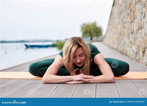 Young Blond Woman Wearing Green Overall With Bare Feet Doing Yoga Pose