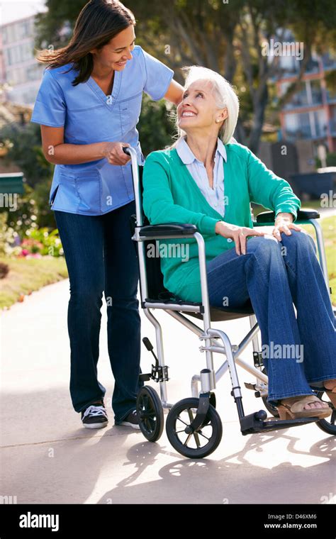 Carer Pushing Senior Woman In Wheelchair Stock Photo Alamy