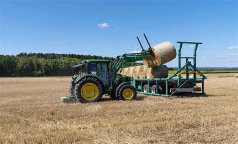 Tractor On A Stubble Field Loads Bales Of Straw Onto A Trailer Stock