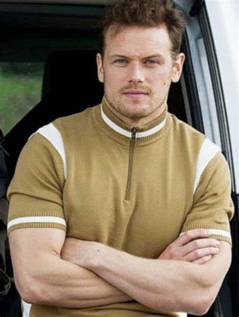 A Man Standing In Front Of A Car With His Arms Crossed And Looking At