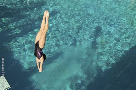 Active female diver diving upside down into the swimming pool Stock ...