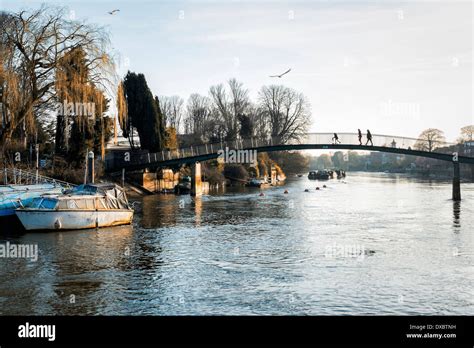 People Walking Across Pedestrian Bridge Over The Thames River To Eel