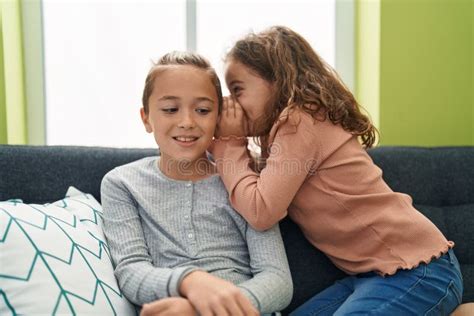 Two Kids Telling Secret Sitting On Sofa At Home Stock Photo Image Of