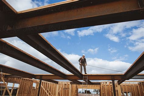 Carpenter Man Measures Board Up On Steel Beams By Stocksy Contributor