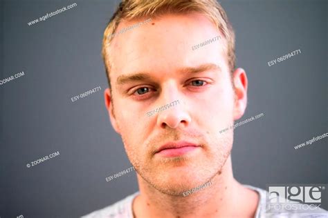 Portrait Of Young Handsome Man With Blond Hair Against Gray Background