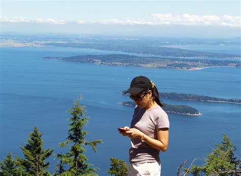 Mature Woman Trying To Use Her Cell Phone While Outdoors Near Th