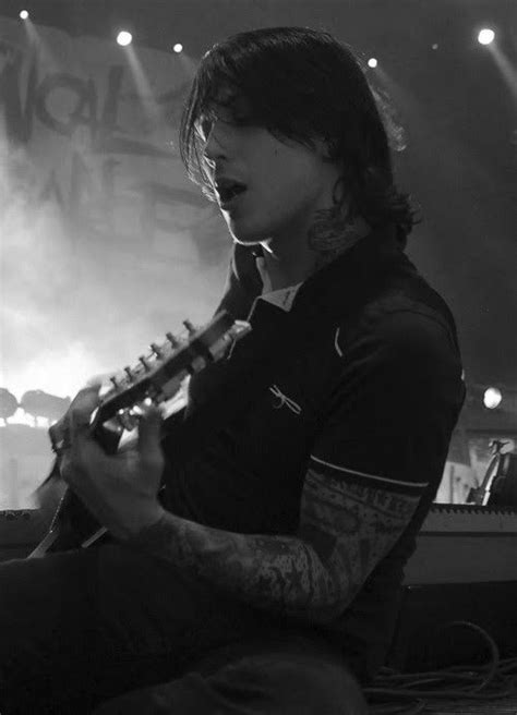 A Man Sitting On The Floor Playing A Guitar In Front Of A Stage With Lights