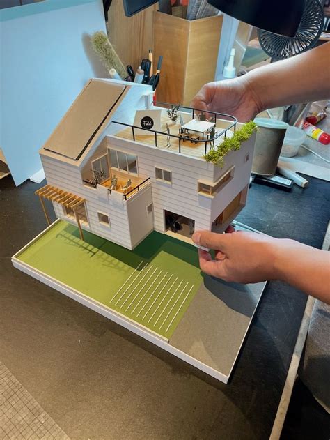 Two Hands Are Holding A Model Of A House