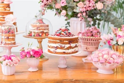 A Table Topped With Lots Of Cakes And Flowers