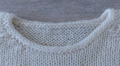 A Close Up Of A Sweater On A Wooden Surface With The Top Stitch Undone